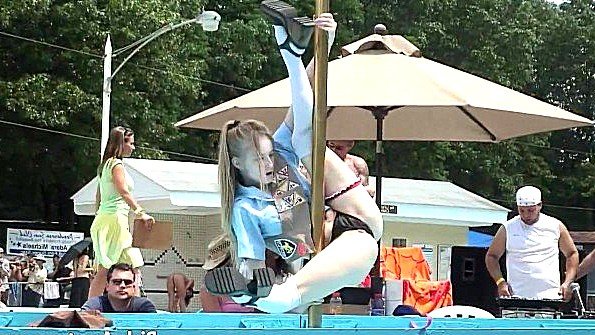 Крутится на шесте перед зрителями и раздевается